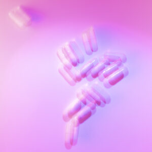 Several pills blurred out on a pink background