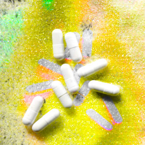 Several white pills on a sparkling yellow background