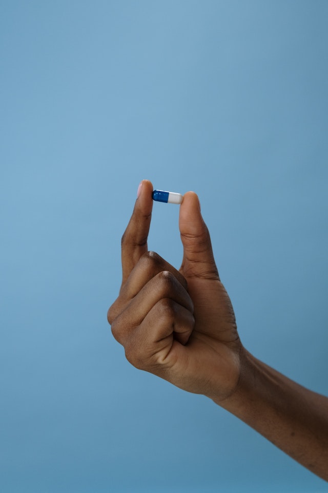 A handing holding a blue and white pill