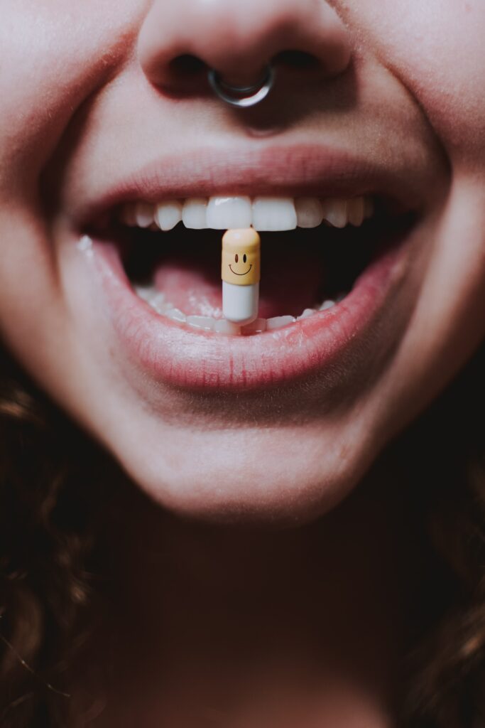 A person holding a pill vertically between their teeth